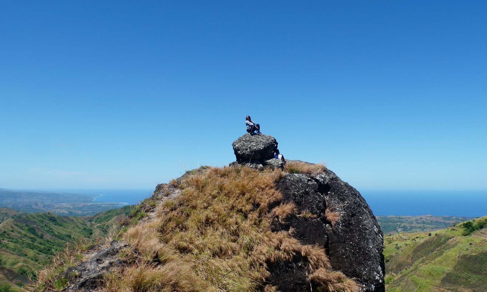 hiker-rests-on-rock-above-landscape