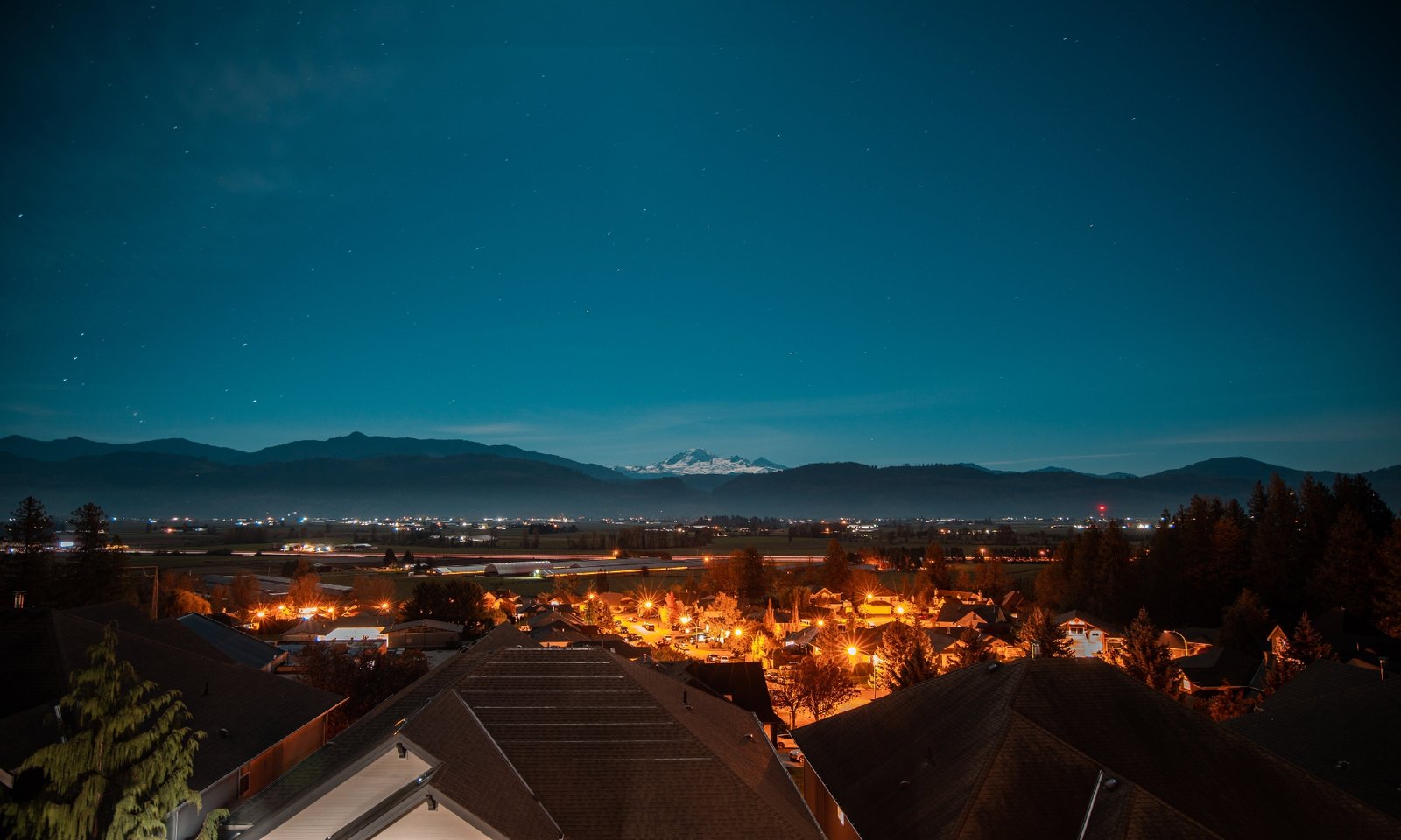 town-looks-out-to-snow-capped-mountains-and-a-starry-sky